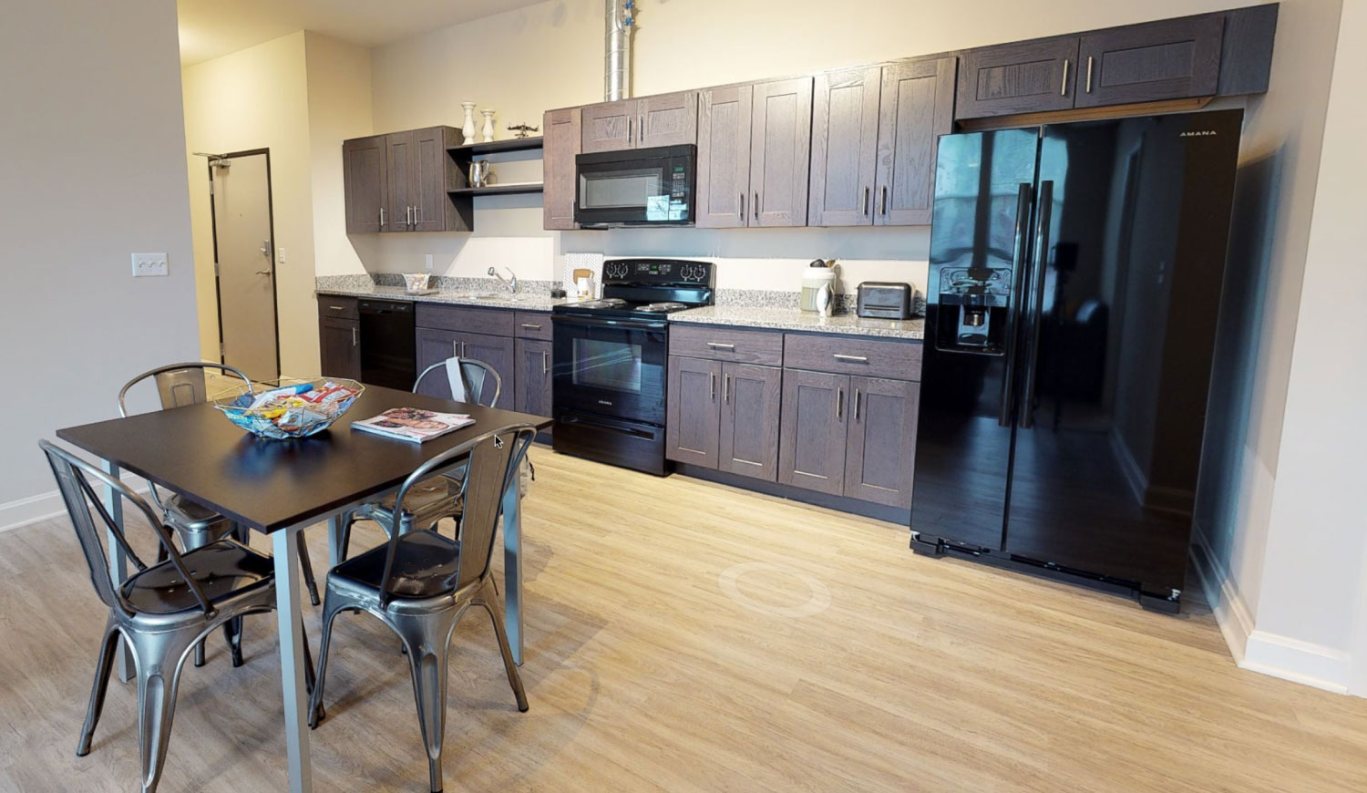 Kitchen with wood-like flooring black appliances and a table