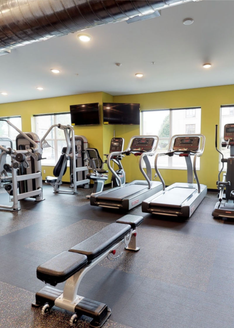 Fitness room with a variety of workout equipment and TVs